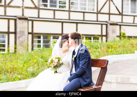 Couple de mariage romantique assis sur un banc dans le parc Banque D'Images