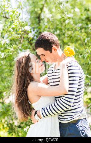 Couple d'amoureux sous les branches en fleurs de printemps. Jeune adulte brunette woman meditating in fresh Apple Blossom ou jardin cerisiers doux baiser. Banque D'Images