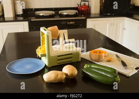 Cuisine familiale avec un spiralizer sur le plan de travail à côté de pommes de terre, courgettes ou courgette et courge Butternut Banque D'Images