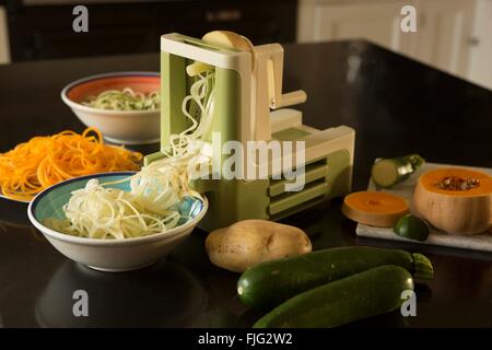 Un spiralizer dans une cuisine domestique avec les courges, courgettes et pommes de terre les deux ensemble et spiralised ou nouilles ou renforts spiralés Banque D'Images
