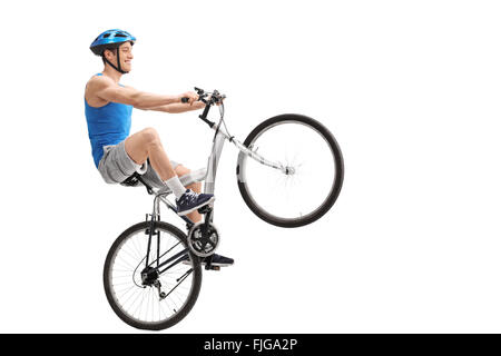 L'exécution d'une jeune cycliste wheelie avec un vélo isolé sur fond blanc Banque D'Images