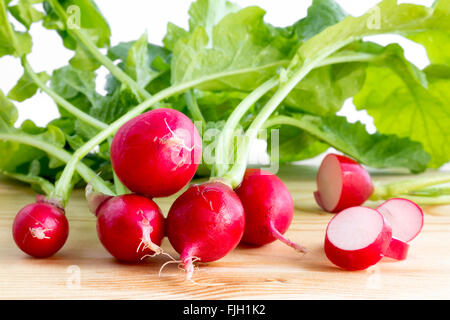 Des tas de radis, Raphanus sativus, sur plaque de bois prêt à manger ou ajouter dans les salades en bonne santé Banque D'Images