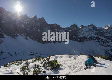 Les alpinistes assis sur un versant de montagne dans la neige en prenant un bain de soleil et regarder au Karwendel Tirol, Autriche, Banque D'Images