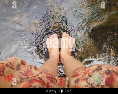 Vue du haut de la jambe et les pieds des femmes plongeon dans l'été, cours d'eau cristalline sentiment de détente Banque D'Images