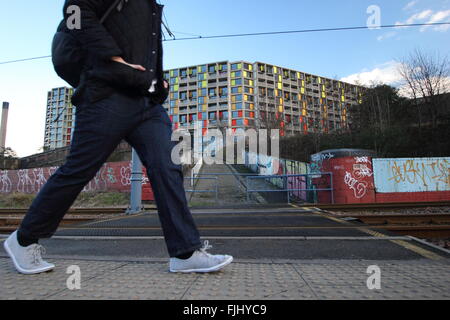 Un homme marche par le tramway près de Park Hill housing estate (photo) dans le centre de la ville de Sheffield, Yorkshire UK Banque D'Images