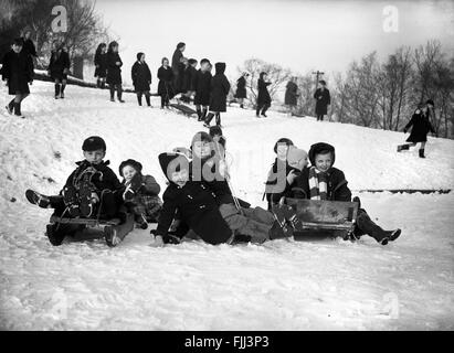 Les écoliers traîneaux et jouant dans la neige pendant la pause Temps Angleterre Grande-Bretagne années 1960 hiver 1961 jouer amusant Royaume-Uni Banque D'Images