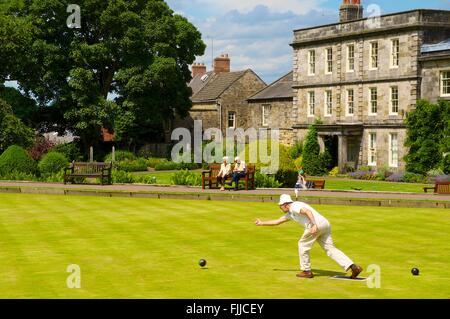 Boules sur pelouse. Homme roulant son bol. Bowling Club House Hexham, Hexham, Northumberland, Angleterre, Royaume-Uni, Europe. Banque D'Images