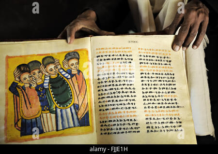 Prêtre orthodoxe, montrant une vieille chèvre illustré livre trouvé sur le site de Yeha, région du Tigré, en Ethiopie Banque D'Images