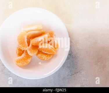 Tranches de mandarine entassés dans un bol blanc à partir de ci-dessus. Banque D'Images