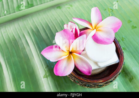 Mini jeu de douche savon avec des fleurs de frangipaniers sur des feuilles de banane verte Banque D'Images