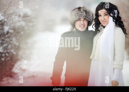 Mariage d'hiver, deux jeunes mariés asiatiques exotiques, groom dans fur hat, bride wearing manteau d'hiver. Banque D'Images