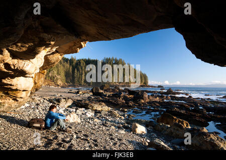 Randonneur dans une caverne sur Sombrio Beach - parc provincial Juan de Fuca, l'île de Vancouver, Colombie-Britannique, Canada Banque D'Images