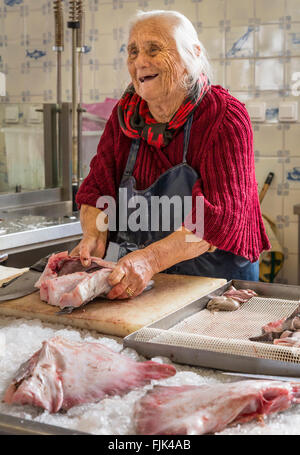 Sympa, souriant vieille femme poissonnier de préparer le poisson frais à vendre au marché public, Cascais, Portugal Banque D'Images