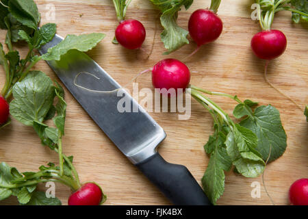 Les radis entiers avec knife on cutting board Banque D'Images