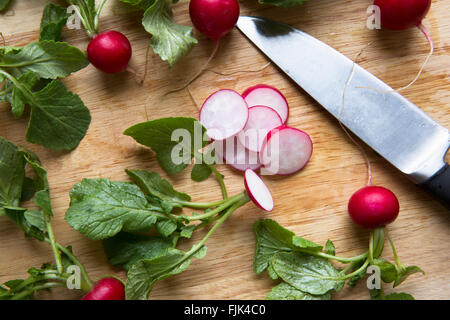 Tranches de radis radis ensemble et à l'aide d'un couteau sur une planche à découper. Banque D'Images