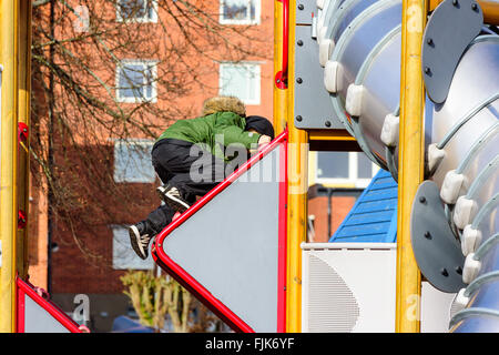 Solvesborg, Suède - 27 Février 2016 : un enfant est grimper à l'extérieur d'une diapositive de se lever. Il met dans un certain effort et n'est p Banque D'Images