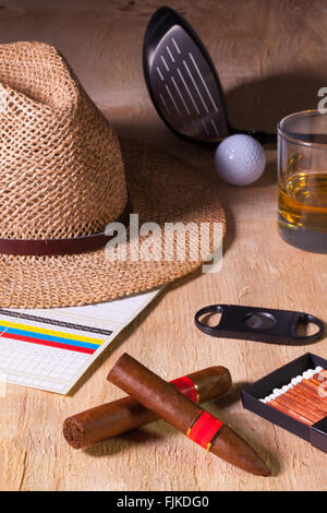 Siesta - cigare, chapeau de paille,whisky écossais et le golf conducteur sur une table en bois Banque D'Images