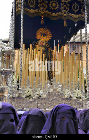 Les processions de nazarenos marcher dans les rues la nuit pendant la Semaine Sainte de Malaga, en Espagne. Banque D'Images