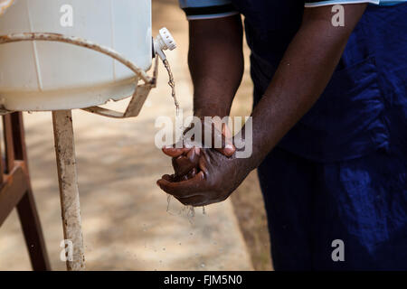 Un homme s'en lave les mains d'un robinet fait maison, en Tanzanie. Banque D'Images