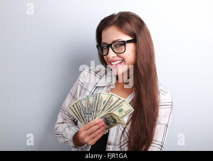 Happy business woman in glasses holding dollars dans la main avec dents smiling on blue background Banque D'Images