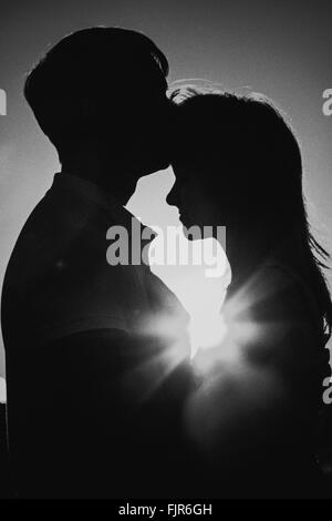 Photographie noir blanc silhouette romantique et couple kissing on meadow background sunset Banque D'Images