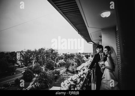 Photographie noir et blanc beau jeune couple debout sur le balcon Banque D'Images