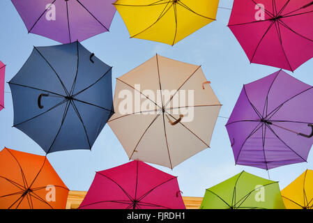 Affichage des parasols colorés Silhouetté contre le ciel bleu. Le Street Art ou art de l'installation dans les rues d'Arles, Provence, France Banque D'Images