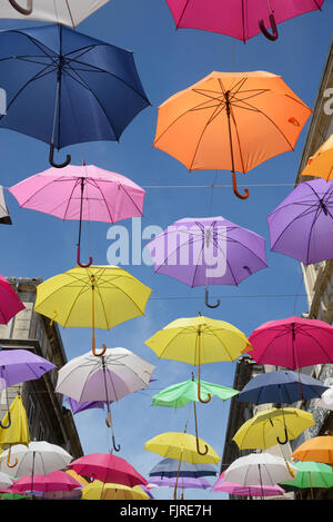 Affichage des parasols colorés Silhouetté contre le ciel bleu. Le Street Art ou art de l'installation dans les rues d'Arles, Provence, France Banque D'Images