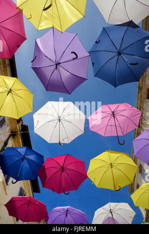 Affichage des parasols colorés Silhouetté contre le ciel bleu. Le Street Art ou art de l'installation dans les rues d'Arles, Provence, France Banque D'Images