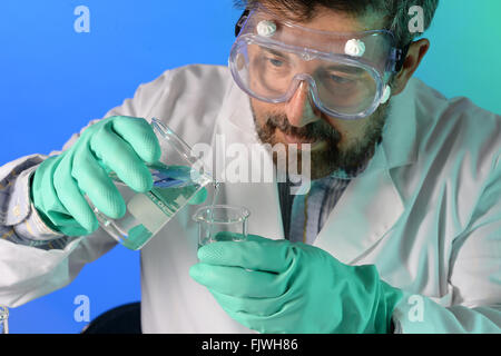 Le mélange des produits chimiques scientifique d'un bécher dans un autre laboratoire en Banque D'Images