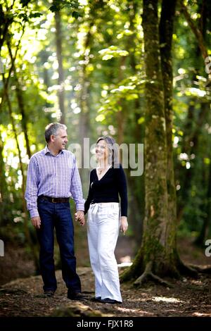 Couple dans les bois au milieu de la nature, tenant les mains, heureux, des sourires, de l'amour Banque D'Images