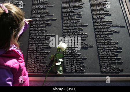 Belfast, Royaume-Uni. 15/04/2012 - une petite fille à points roses sont posés alors que les noms des victimes sur le centenaire du naufrage du Titanic, et ouverture de la Memorial Garden à Belfast City Hall, au cours de la commémoration du 100e anniversaire et memorial le dévouement de la catastrophe du Titanic à Belfast, en Irlande du Nord, le 15 avril 2012. Le navire a heurté un iceberg dans l'Atlantique Nord sur son voyage inaugural le 14 avril 1912, avec la perte d'environ 1 500 vies. Il a été construit à Belfast's naval Harland and Wolff. Photo/Paul McErlane Banque D'Images