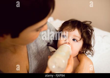 Mignon bébé bouteille étant alimenté par sa mère Banque D'Images