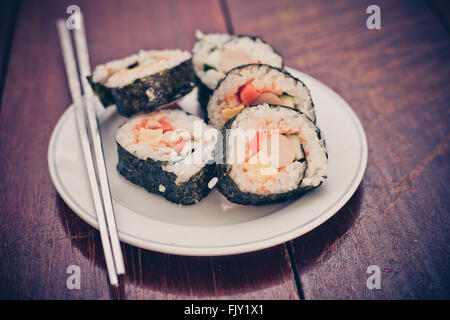 Rouleaux de sushi de riz assortiment sur plaque blanche et grise baguettes Banque D'Images