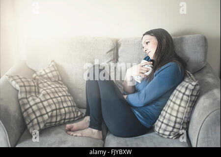 Jeune femme se reposant dans un canapé-lit Banque D'Images