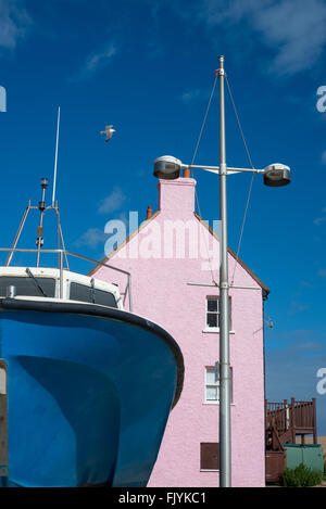 Un bateau et maison rose au port de West Bay, Dorset, Angleterre Banque D'Images