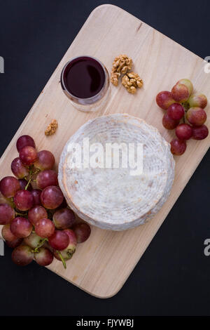 Tête de fromage moulé blanc sur une planche à découper en bois accompagné avec verre de vin Banque D'Images