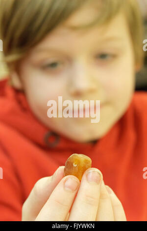 Jeune garçon tenant un morceau d'ambre dans sa main Banque D'Images