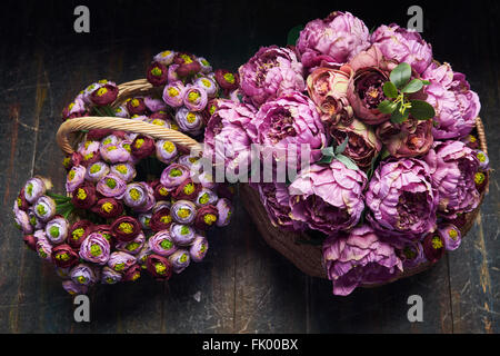 Deux panier plein de pivoines rose et violet , bourgogne , panier avec poignée est sur le plancher en bois, vue du dessus Banque D'Images