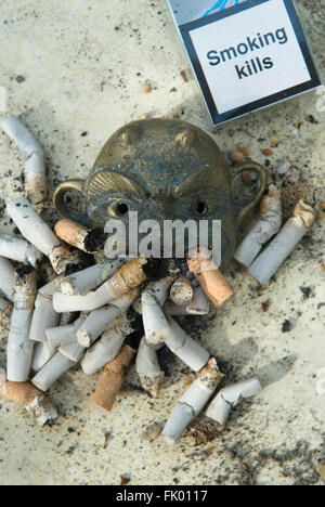 Fumer Kill UK. Santé publique waring. Un paquet vide de cigarettes Sterling avec les Smoking Kills, un cendrier débordant en forme de visage humain et de nombreux mégots de cigarettes. Londres Royaume-Uni 4 mars 2016. HOMER SYKES des années 2010 Banque D'Images