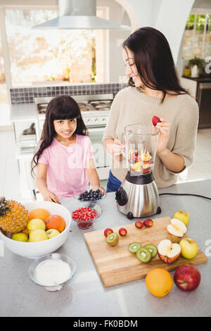 Smiling mother and daughter la préparation de jus de fruits Banque D'Images