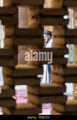 Le mollah Chiite musulmane en turban et une blouse vu à travers l'écran de la brique dans le whilepraying Masjed-e Jame (mosquée du vendredi), Isfahan, Iran Banque D'Images