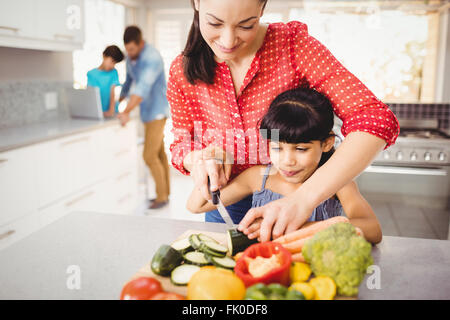 L'enseignement de mère heureuse fille pour couper les légumes Banque D'Images