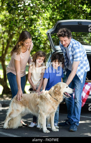 Smiling family standing in front of a car Banque D'Images