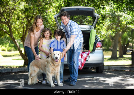 Smiling family standing in front of a car Banque D'Images