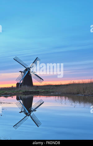 Herringfleet smock mill relecting dans l'eau sur un matin d'hiver brumeux. Banque D'Images