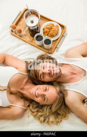 Cute couple au lit à côté d'un plateau de petit-déjeuner Banque D'Images