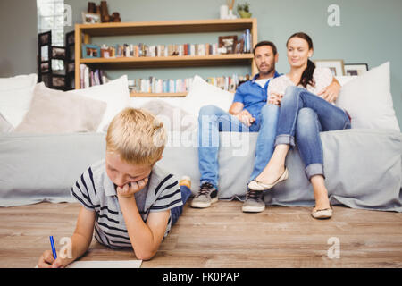 Garçon dessin sur le papier tandis que les parents de le regarder Banque D'Images