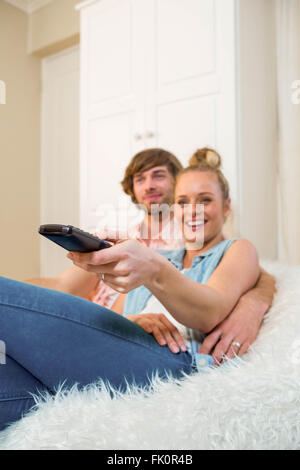 Cute couple regarder la télévision et à l'aide de Remote sur le canapé Banque D'Images