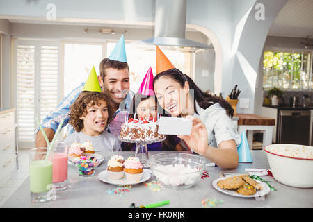 Family smiling tout en prenant de l'anniversaire de selfies lors Banque D'Images